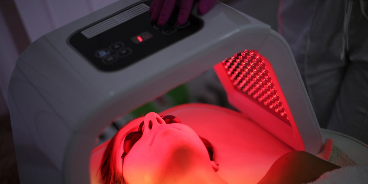 Person undergoing red light facial therapy with protective goggles.