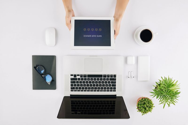 Freelancer sitting at office desk and rating service and leaving feedback after using application on tablet computer