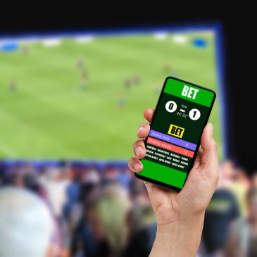 Hand holding phone with live sports app during a football match.