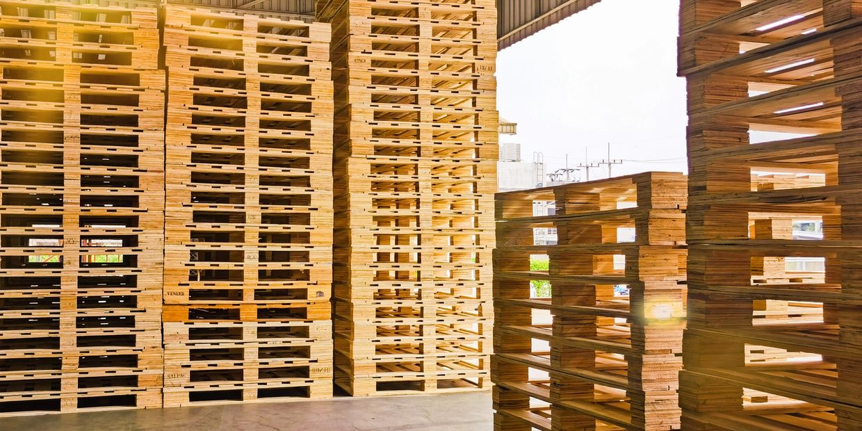 Stacks of wooden pallets neatly arranged inside a warehouse.