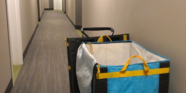 A blue and yellow cart is parked in a long, narrow hallway with closed doors.