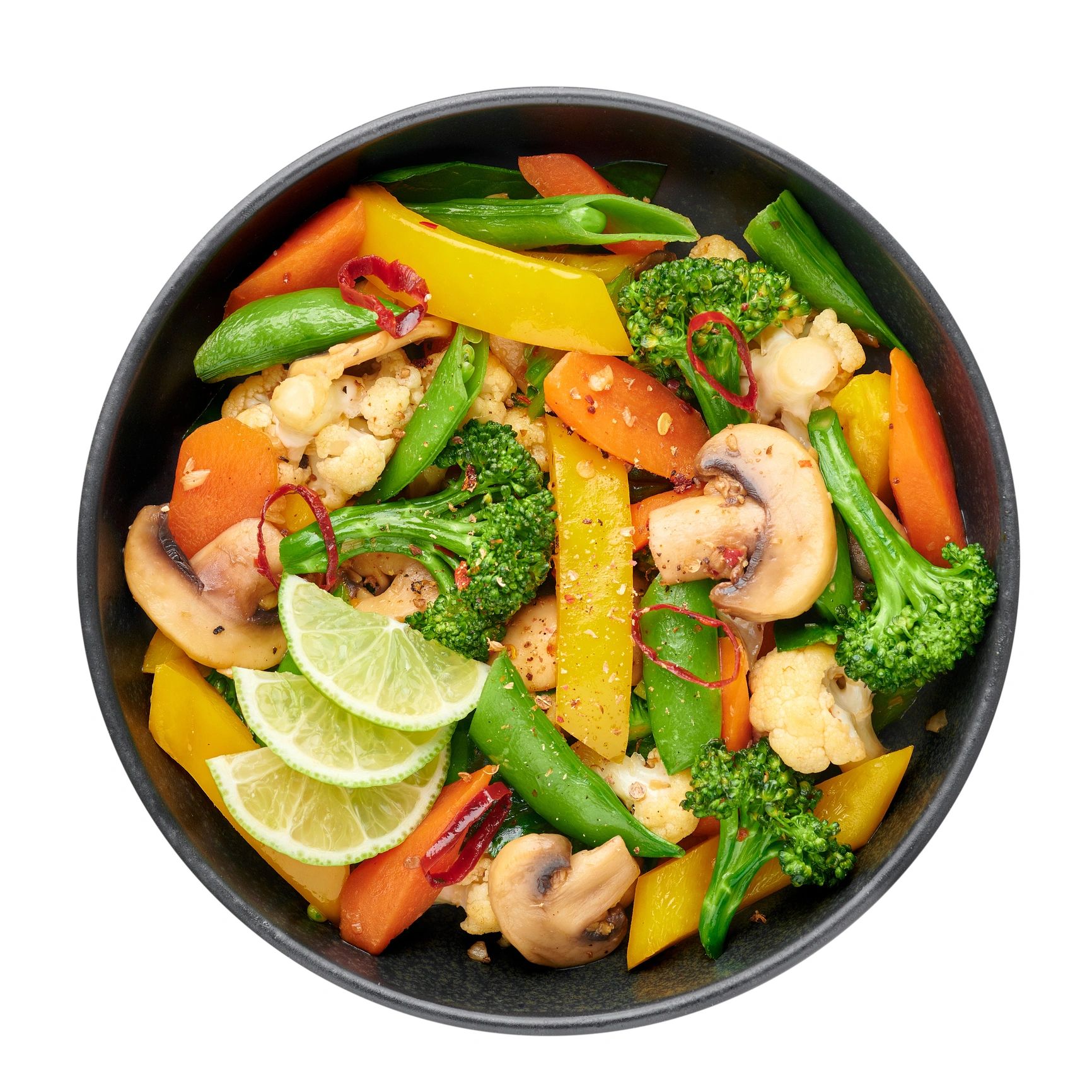 Fresh vegetable stir-fry with lime wedges in a black bowl.