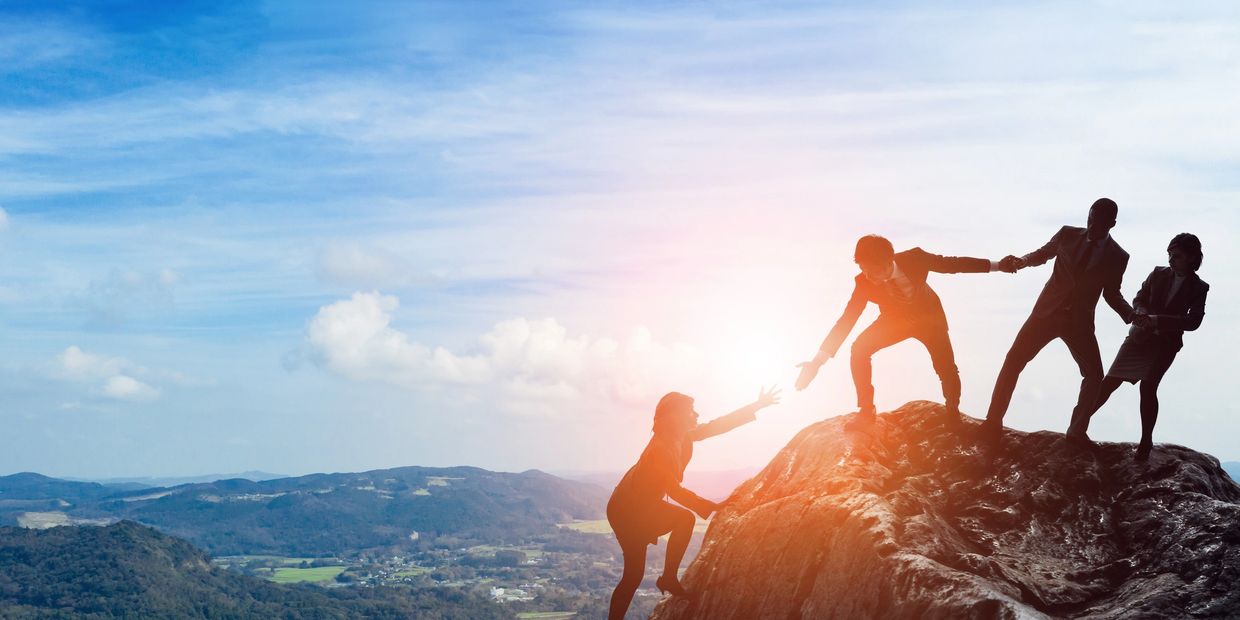 Team working to stay together on top of a mountain.