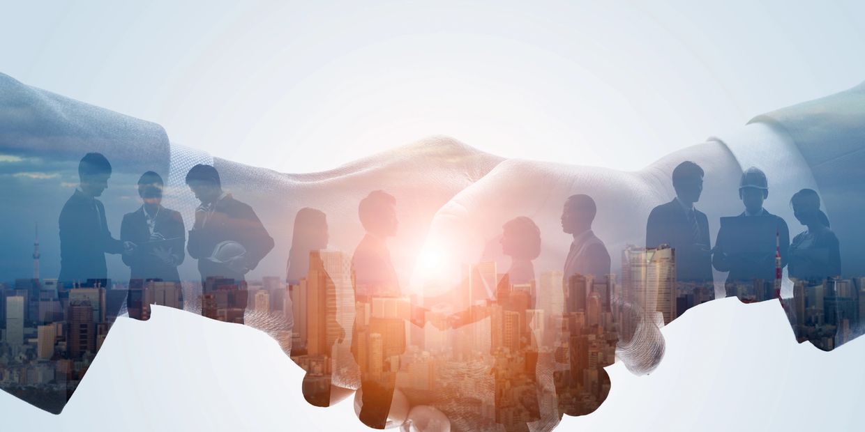 Double exposure of handshake and business teamwork in cityscape.