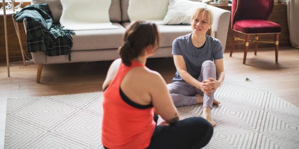 Two women sitting on the floor, engaging in conversation.