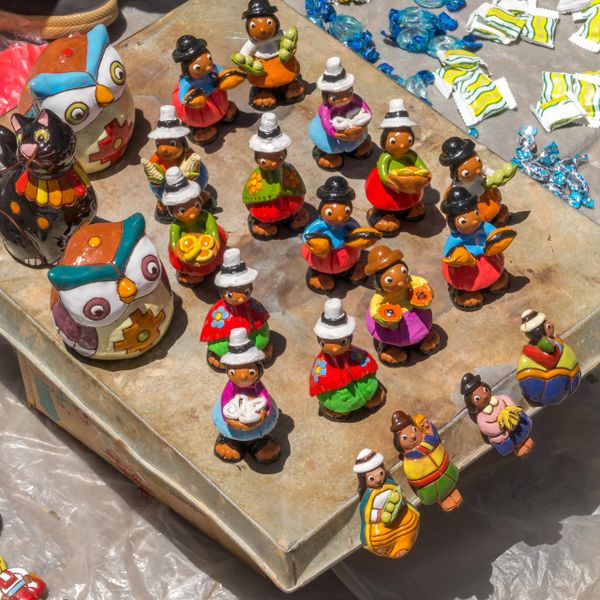 Colorful handcrafted figurines and owl pottery displayed on a table.