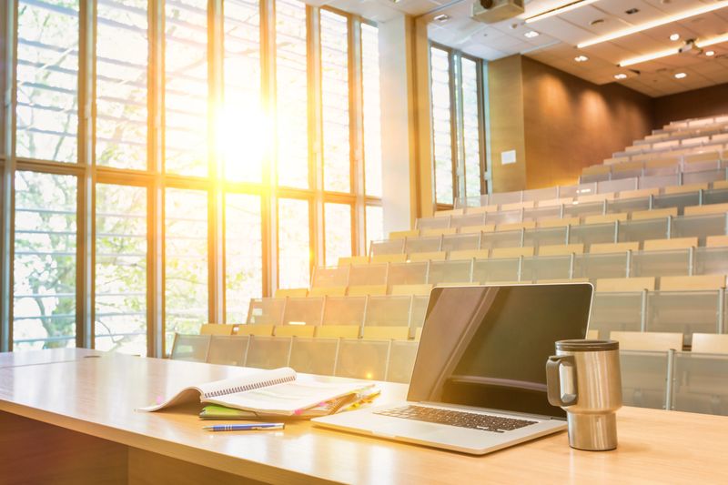 Photo of laptop on professor desk in lecturer theatre in college university