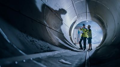 Engineers inspecting the interior of a large underground tunnel.