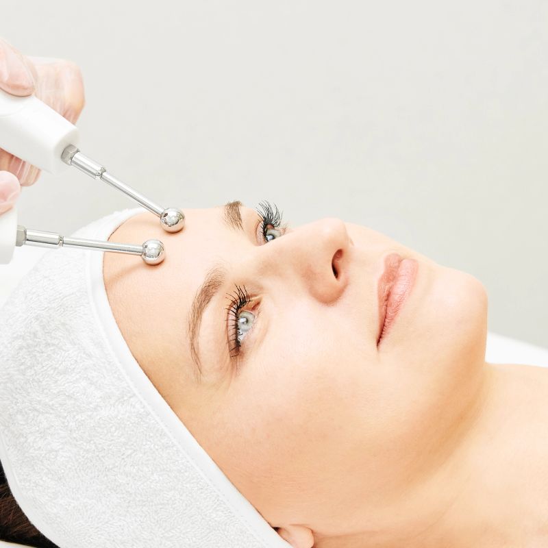 Microcurrent esthetics procedure. Beauty girl face. Cosmetology machine. Doctor hands. Two micro balls. Wrinkle reduction.