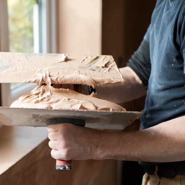 A man spreading plaster between two trowels