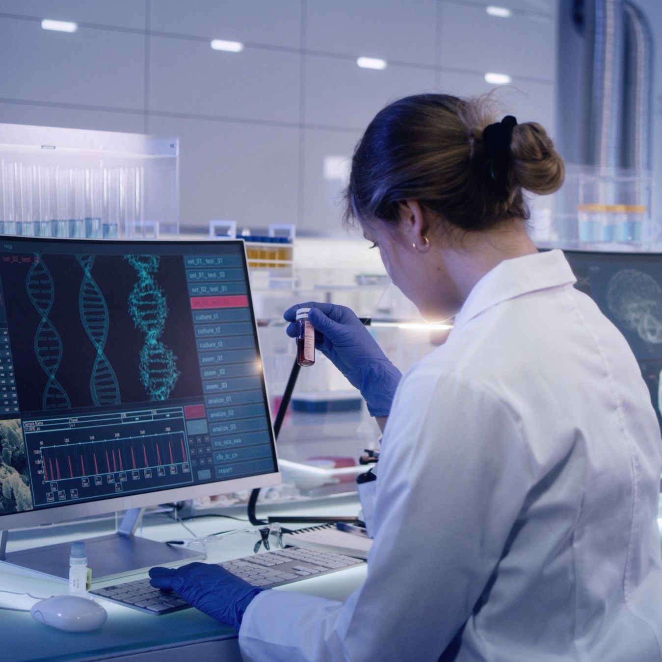 Scientist analyzing DNA data on a computer screen in a lab.