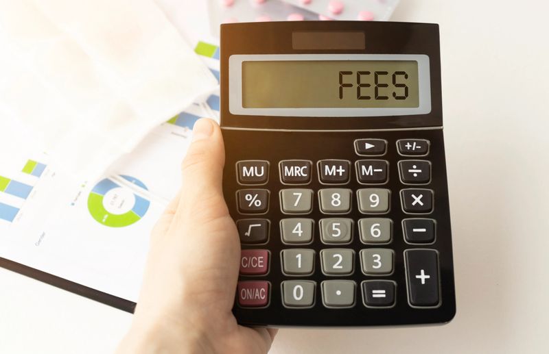 A calculator with the inscription FEES is placed in the stack of documents. Business concept