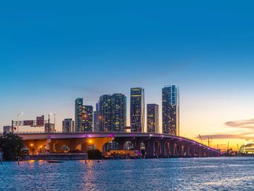 City skyline with a bridge over water at sunset.