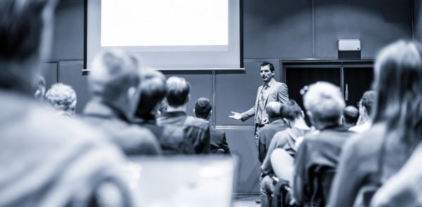 Speaker presenting to an audience in a conference room.