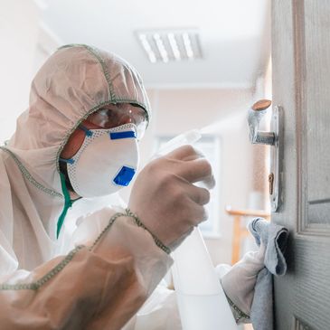 Mold remediation technician wearing protective equipment while treating an affected wall.