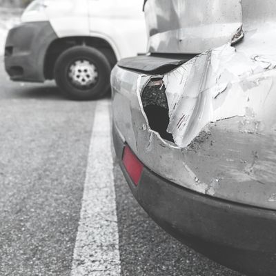 Close-up of a car with a severely damaged rear bumper and a deep dent.