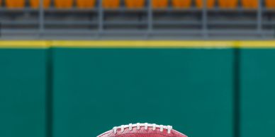 American football on the field in front of empty stadium seats.