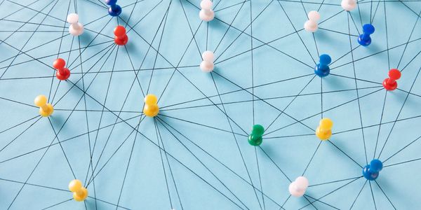 Colorful push pins connected by black strings on blue surface.