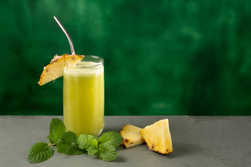 glass cup with pineapple juice and mint on a slate surface.