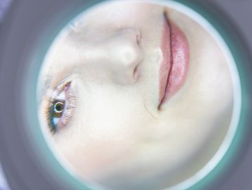 Close-up of a woman's face through a circular lens.