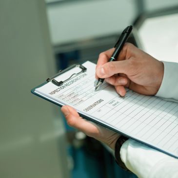 Person filling out inspection records on a clipboard.
