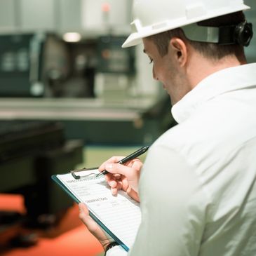 Engineer filling an inspection report on a clipboard in an industrial setting.
