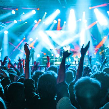 Crowd enjoying a vibrant live concert with bright stage lights.