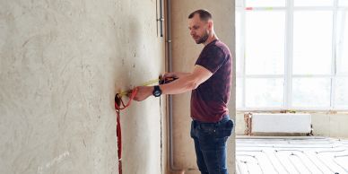 A man working on electrical wiring in a room under renovation.