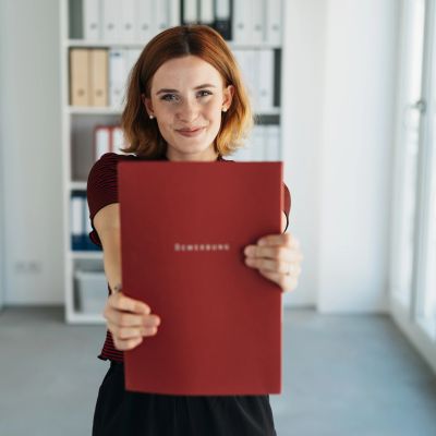 Woman holding a red folder and smiling.