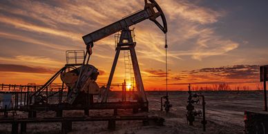 Oil pumpjack silhouetted against a vibrant sunset sky.