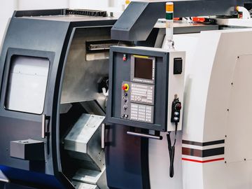 A CNC machine with control panel in an industrial setting.