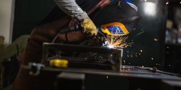 Welder using protective gear creating sparks.