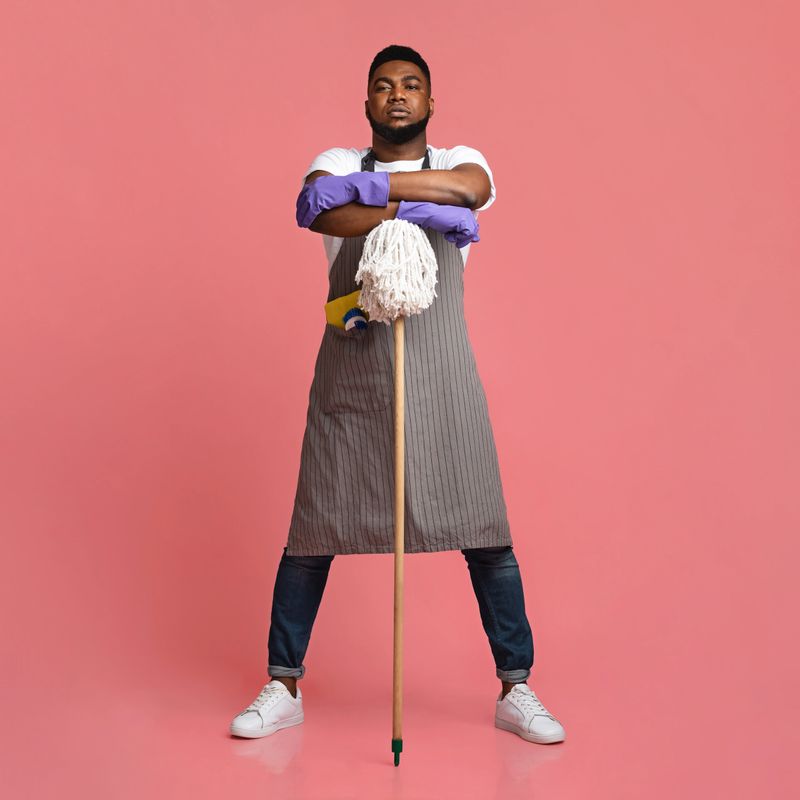 On Guard Of Cleanliness. Professional African American Cleaner Posing With Mop Over Pink Background In Studio, Ready For Big Cleaning