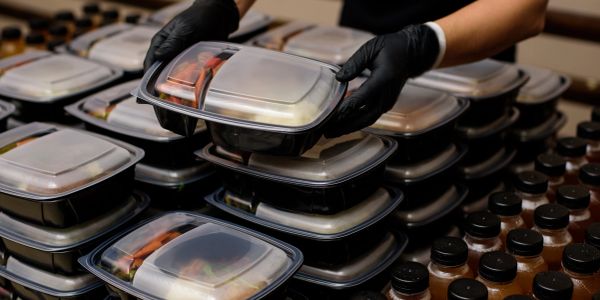 Person arranging meal prep containers with drinks.