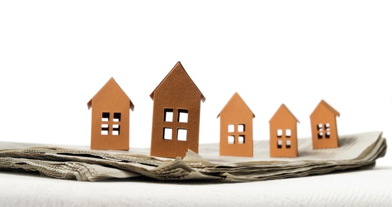 Open newspaper with paper houses. Concept of rent, search, purchase real estate.