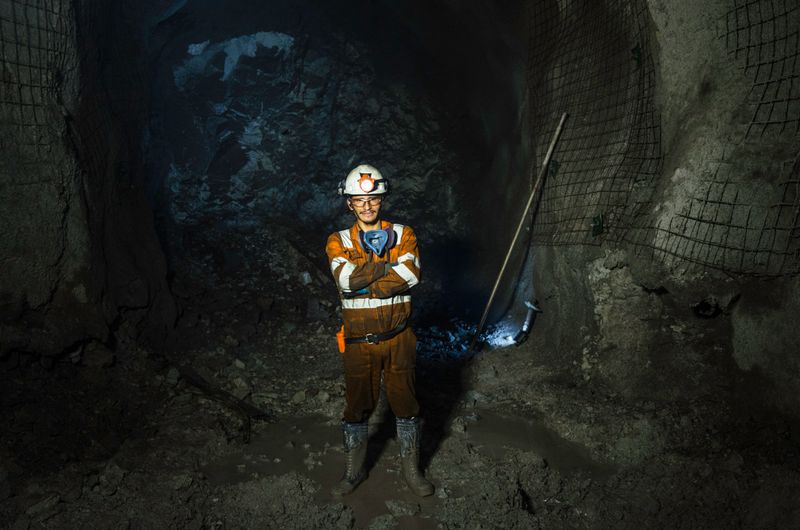 Miner in the mine. Well-uniformed miner inside mine raising thumb, conceptual photo