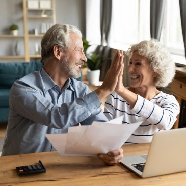 Older couple celebrates financial success with high five.