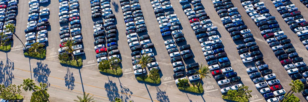 Aerial view of a large parking lot filled with cars and palm trees.