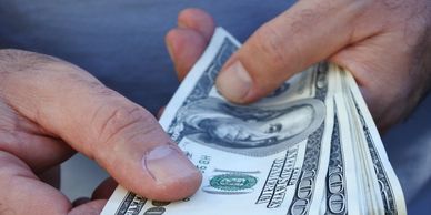 Hands counting multiple hundred-dollar bills.