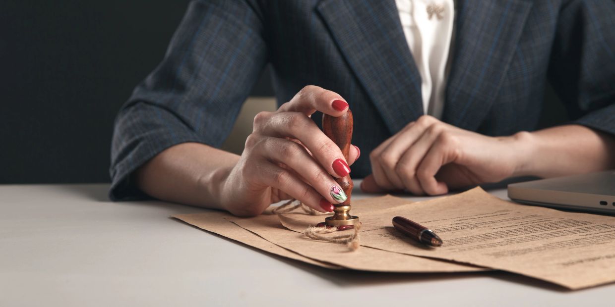 Person sealing a document with a wax stamp.