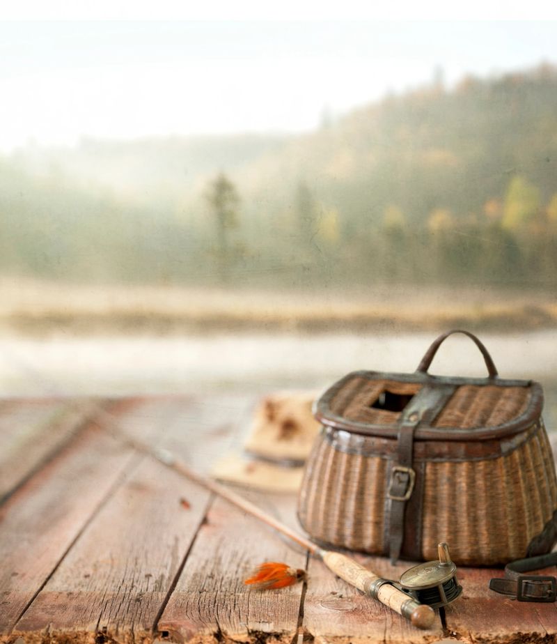 Vintage Wicker Creel and Fly Fishing Equipment Set against a Natural Scenic Background