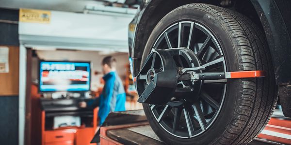 Car wheel with alignment tool attached in a garage.