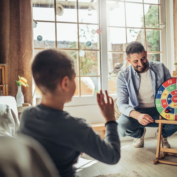 Father teaching son how to throw darts