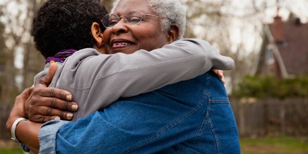 Two people sharing a warm hug outdoors.