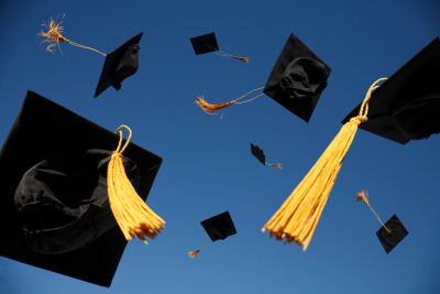 Birretes de graduación volando al cielo.