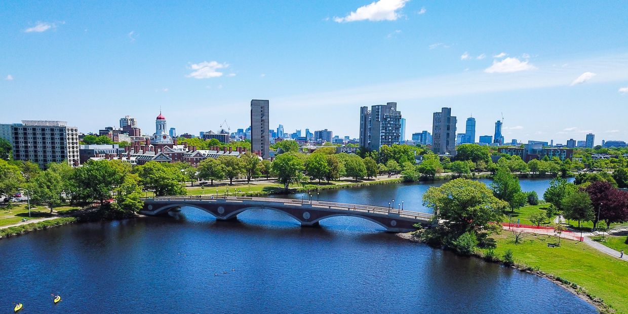 A scenic bridge over a river with city skyline and kayakers in the distance.