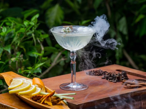 Elegant cocktail with smoky garnish on wooden board.