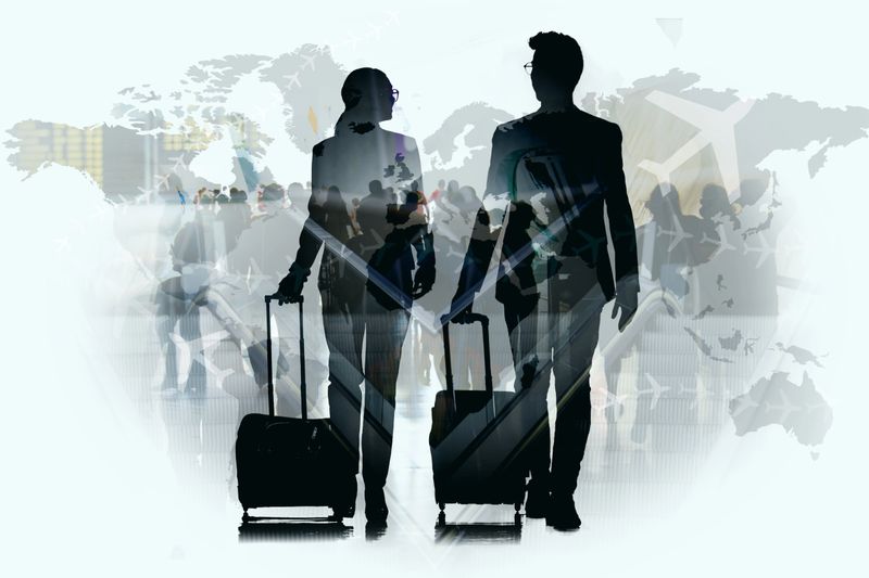 Double exposure of silhouette of two young business partners walking and talking through the airport hall over world map background.