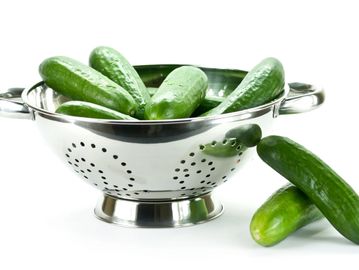 Fresh cucumbers in a metal colander.