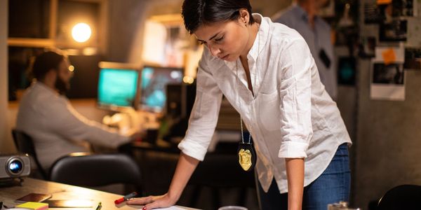 Detective examining evidence and documents in a dimly lit office.